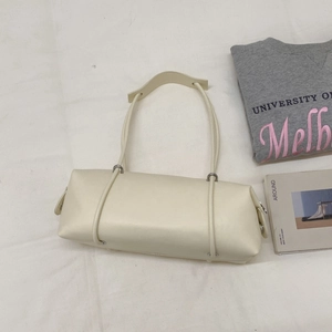 Minimalist beige leather tote bag displayed on fabric with lifestyle props and casual outfit