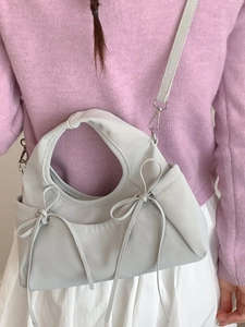 Chic pleated cloud bag with bow accents and top handle in cream faux leather