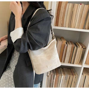 Détail du sac seau tissé beige avec bandoulière en cuir dans un cadre de vie chic