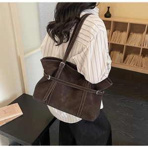 Close-up of a large coffee brown tote bag with contrast stitching and buckle detail
