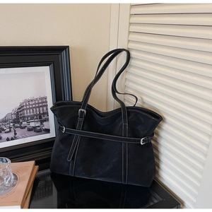 Close-up of black leather tote bag with stylish white contrast stitching and silver buckle