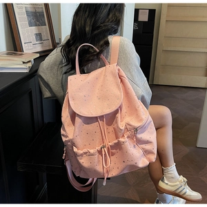 Detail of pink backpack with silver star patterns showing drawstring and flap closure