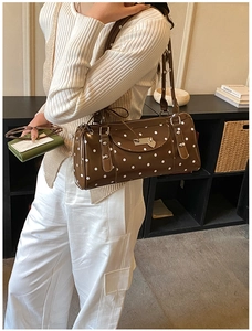 Detail view of retro brown polka dot underarm bag with silver heart charm and buckles