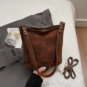 Détail du sac seau en tissu texturé avec bordure en cuir et bandoulière réglable