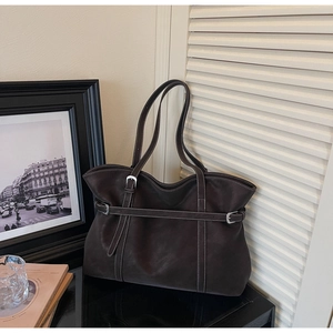 Detail view of brown tote bag with white contrast stitching and silver metal buckle