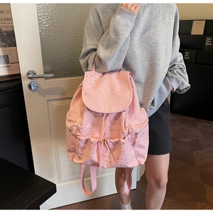 Pink drawstring backpack with silver star print shown in a lifestyle indoor setting