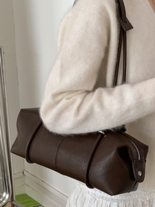 Minimalist dark brown cylindrical tote bag for women worn by model in white outfit