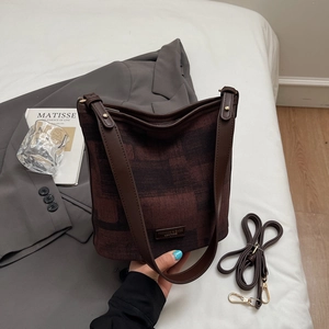 Détail du sac seau vintage avec motif texturé, bandoulière en cuir et étiquette mode