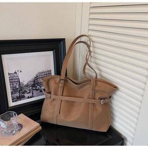 Close-up of camel tote bag with white contrast stitching and buckle strap detail