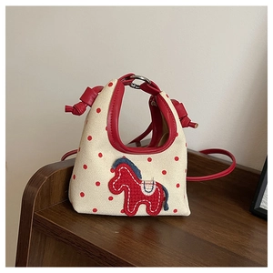 Close-up of mini canvas handbag with red polka dots and embroidered pony patch