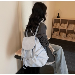 Detail of light blue backpack featuring silver star patterns and drawstring closure