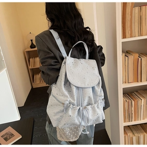 Close-up of light blue star print backpack with functional drawstring and flap detail