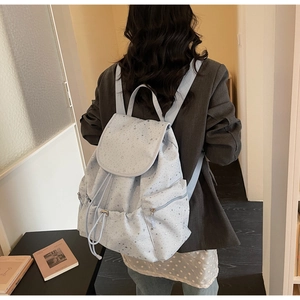 Detail of light blue starry backpack with drawstring closure and silver star patterns
