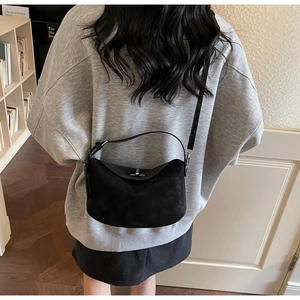 Détail du sac demi-lune en daim noir montrant le fermoir rotatif et l'anse courte