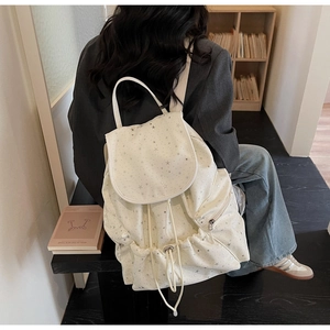 Detail of white canvas backpack with silver star print and drawstring closure design