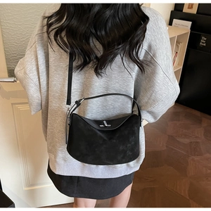 Gros plan du sac à main en cuir noir mat avec fermoir argenté sur l'épaule