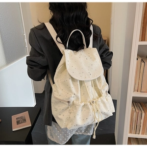 Detailed back view of a beige canvas backpack with star prints and metal zip pockets