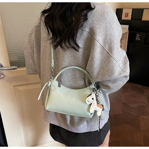 Détail du sac à bandoulière en cuir vert menthe avec cordon nœud et breloque poney