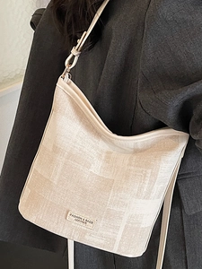 Sac seau minimaliste en cuir beige avec bandoulière réglable sur blazer gris chic