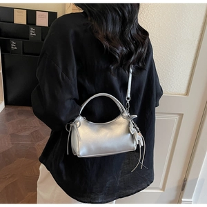 Détail du sac demi-lune argenté avec breloque chat, cordon nœud et bandoulière réglable
