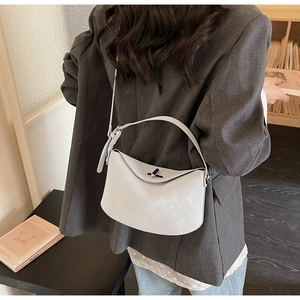 Sac croissant en cuir gris clair minimaliste porté par mannequin en costume