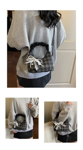 Detail of grey plaid crossbody bag with pleated handle and white lace pearl bow charm
