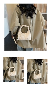 Detail view of cream pleated handbag with lace bow charm and heart pendant accessory