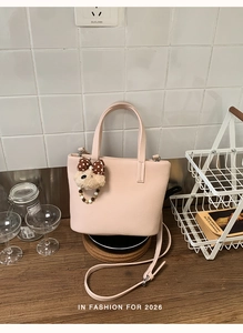 Detailed view of pink leather tote bag with cute plush bear charm and beaded accessory