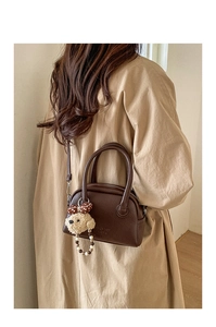 Detail of dark brown lychee leather bowling bag with cute puppy plush charm accessory