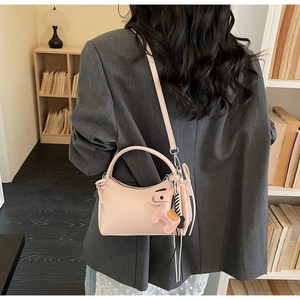 Détail du sac à bandoulière rose avec charm cheval et accessoire rayé en intérieur