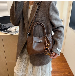 Close-up of vintage dark brown tote with matte leather texture and colorful bead charm