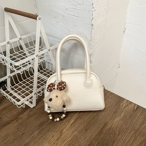 Dettaglio borsa bowling beige in pelle litchi con ciondolo a cucciolo e perline colorate