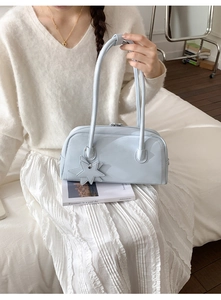 Close-up of light blue shoulder bag with star charm detail on a minimalist model