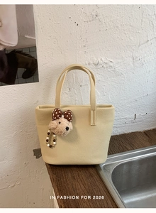 Detail of cream leather tote bag with lychee texture and cute plush bear charm