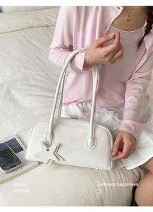 White faux leather bowling shoulder bag with star pendant on a soft pink knit background