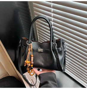 Close-up of black litchi pattern leather bag with vintage wooden beads and silver lock