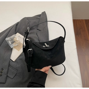 Gros plan d'un sac oreiller en daim noir avec fermoir argenté et bandoulière