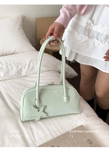 Detail view of mint green leather tote bag with star charm on white linen background
