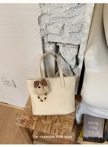 Close-up of beige tote bag with a cute teddy bear charm and brown polka dot bow