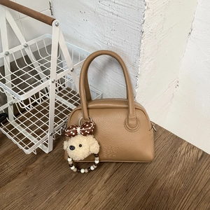 Dettaglio di borsa bowling in pelle marrone con ciondolo a forma di cane in peluche