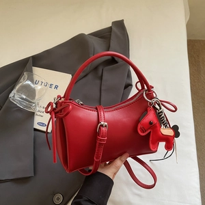 Détail du sac rouge avec boucle argentée et charm de cheval dans un cadre élégant