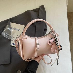 Sac à main en cuir rose avec poignée ronde et charm de cheval sur fond minimaliste moderne
