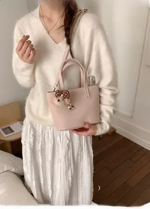 Detail of pink lychee leather handbag with cute teddy bear charm and metal strap buckle