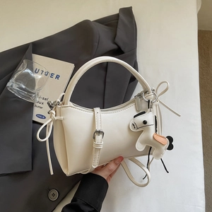 Détail d'un sac à main minimaliste en cuir blanc avec un charmant pendentif de poney