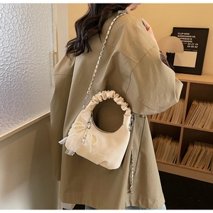 Close-up of pleated handle handbag with pearl tassel and lace detail in a home setting