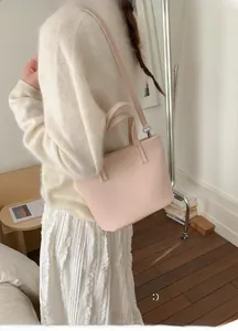 Detail view of pink leather tote bag featuring dual handles and adjustable shoulder strap