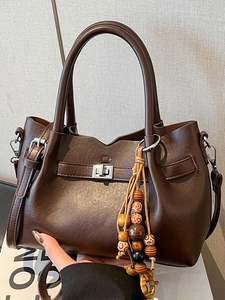 Brown faux leather handbag with silver turn-lock and colorful ethnic bead charm