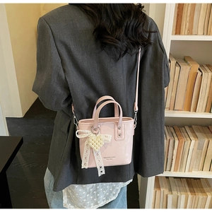 Mini borsa a secchiello rosa con ciondolo a cuore di perle e fiocco in pizzo in scena