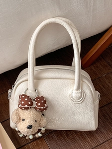 Borsa a bauletto bianca in pelle con ciondolo a orsetto su parquet scuro