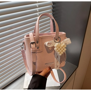Dettaglio della borsa in pelle rosa con ciondolo a cuore in perle e fiocco in pizzo